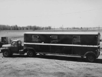 The “Cattle Cars”. As the working population at the Plant began to grow, there was the need for more and larger vehicles for transporting staff from Deep River, Pembroke and Chalk River to the Plant site. The “buses” are described in the June 1967 issue of AECL Review thus: “For a while, back in 1945, three tractor trailer units were used to carry employees from Pembroke to the Plant and from Pembroke to Deep River. These vehicles were dubbed “cattle cars” by those who used them and the name wasn’t inappropriate. Standard long-haul trailers, they had a few windows near the roof for ventilation;” and “Benches ran the length of the trailer on each side and across both ends. One of the Fraser Brace employees acted as conductor. In addition to punching tickets and opening and closing the doors for the pick-up and delivery of passengers, the conductor was expected to fire the box stove. A Quebec heater, this stove was the only source of heat in the trailer. The conductor was also responsible for counting the passengers, not an easy task when the count ran up to 90 and often included standees.” We also learn: “The fleet at this time included 10 new buses each with a seating capacity of 33, in addition to the three “cattle cars”. Road conditions were often questionable, the article continues: “In the spring of 1945 the Plant road was impassable at one point. Buses were unloaded, the passengers walked across the rough section, and were picked up by trucks for the remainder of the trip”.Photo source – AECL. 103-1000