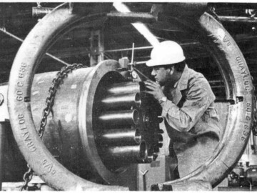 D. Legros working on the assembly of a prototype fueling machine head at the Power Projects lab. The head will hold 12 fuel bundles.<br /><br />Photo source – AECL Review, September 1964. 105-1000