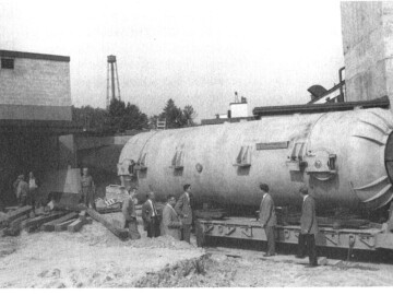 The pressure vessel of world’s first tandem Van de Graaff arriving at CRNL in 1959. The EN “tandem” was an advance on the 3.5 MV accelerator not only in the fact that it was a higher voltage unit (nominally 5 MV) but also that it was a “tandem”. In these machines the positive high-voltage terminal is in the middle of the accelerator. Negative ions are accelerated from the ion source to the terminal where they pass through a foil, are stripped of a number of electrons and are then repelled back to ground potential. For example, an oxygen atom injected with a -1 charge might be stripped to a +5 state in the terminal and would hence get a total energy of 30 MeV. Photo source – AECL 105-1000