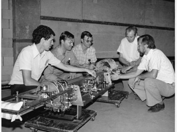The prototype 25 MeV accelerator. The prototype accelerator developed at CRNL shown just before shipping to CPD for incorporation into a gantry and control system. L-R. E. Heighway, W. Funk, R. Hutcheon, S. Hodge and S. Schriber. See link (AA5). A number of commercial versions of the accelerator, called the THERAC 25, were sold by CPD but were later removed from service because of a serious accident resulting from software and control system errors. The accidents have been the subject of a great deal of investigation in the use of computer control for safety-critical applications. An excellent review of these investigations has been published by N.G. Levenson and C.S. Turner. See link (AA6).
<br /><br />
Photo source-AECL. 109-1000