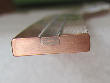 Cross-sectional view of the conductor used in the cyclotron windings. Niobium-titanium superconductor multifilaments are imbedded in a 4 mm by 2mm copper matrix which is then soldered into a 16mm by 4 mm copper strip suitable for winding. The superconductors were held at a temperature of 4.5 K using a liquid helium coolant and had a current density of 3400A/cm2. Photo source – the Society. 111-1000