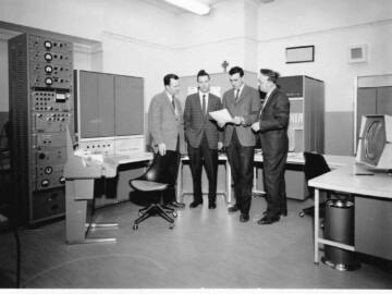 In the early 1960s the opportunity for using computers not only for data gathering and numerical calculations but also as critical parts of control systems for large experimental facilities was recognized. The Digital Equipment Corporation (DEC) had been producing a series of logic modules and its customers and engineers convinced the management to combine these modules into a “control computer”. The following is extracted from link C7: “One of DEC’s oldest computer customers was Atomic Energy of Canada, which had purchased one of the first PDP-1 computers for its Chalk River facility. The company proceeded to buy a PDP-4 to control the reactor at Chalk River, but the computer was not quite able to handle all the duties it had been assigned. To solve this problem, Gordon Bell proposed in early 1963 that rather than create custom circuitry to meet Atomic Energy’s needs, DEC should build a smaller computer that could serve as a front end to interface with the PDP-4 and provide the needed functionality. Rather than just create a system limited to Atomic Energy’s needs, however, Bell decided to design the machine so it could also function as an independent general-purpose computer. DEC named this new computer the PDP-5.” The CRNL PDP-1, which was used at the tandem accelerator facility, arrived at CRNL in 1963. In 1984, after 21 years of service, it was retired and replaced by a Perkin-Elmer 3230. It was donated to the Science North facility in Sudbury. Unfortunately it was later discarded. A number of PDP-1s have been restored at various locations in the USA. Link C8 shows an excellent video of a restored PDP-1 in operation and demonstrates the famous Starwars program being loaded from paper tape and then running on the computer. The photo above shows both the PDP-5 (on the left) and the PDP-4 (on the right) discussed above in the NRU control room with some of the main contributors to the installation.<br /><br />Photo source – AECL. 116-1000