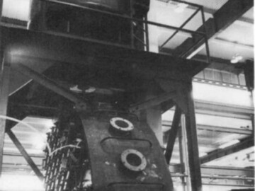 Photo shows a test rig fabricated to test a new concept in reactor end shields. Small steel balls are poured into the hopper at the top and can be seen through the portholes on the end shield shell.
<br /><br />
Photo and caption source – AECL Review, November 1970. 116-1000