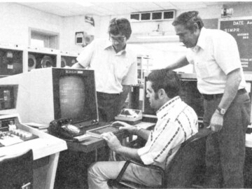 The central-computer control console in 1979. L-R. P. McGandy, B. Ostrom and D. McPherson at the console of what was at that date a combined CDC 6600/Cyber 170 mainframe computer. 117-1000