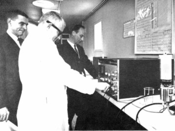 In the 1965-1970 period the Radio Chemical Company established a program to produce small (108-109 n/s) neutron generators for activation analyses. The generators were of the antimony - beryllium type which depend on the decay of Sb124 (half-life of 60 days) to Te124 with the emission of gamma rays above the 1.67 MeV energy threshold needed for the (gamma,n) reaction on Be. A mobile lab, called the Radactan, was developed by Commercial Products to be able to travel to various sites to assist chemists, metallurgists and geologists to analyze ore samples, solutions and alloys for their composition of elements in a few minutes via neutron activation. The equipment was mounted in a 36 foot long trailer that could be easily transported and was built for year-round use. The photo shows (L-R) R. Murphy, P. Kennedy and R. Churchill in the mobile laboratory analyzing a sample.
<br /><br />
Photo source and caption– AECL Review, May 1967. 124-1000-1